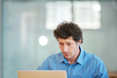 Doing some research online. Cropped shot of a handsome businessman working in the office.の写真素材