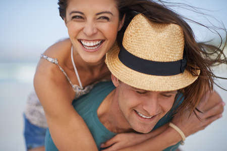 They always have fun together. A young couple piggybacking at the beach.の写真素材