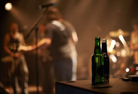 Lets have another. Two beer bottles on a table as a band plays in the background.の写真素材