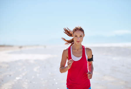 Determined to get fit. Cropped shot of a young woman running on the beach.
