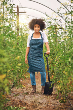 I put in the hard labour. Full length shot of an attractive young female farmer standing in a...