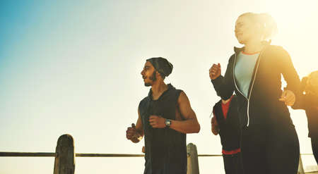 Getting fit with friends. Shot of a fitness group out running on the promenade.