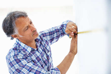 Mature architect taking wall measurement. Closeup of mature architect taking measurement on the...