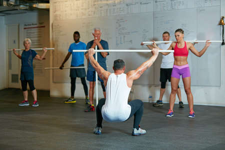 Leading his class. Shot of a fitness group working out at the gym.の写真素材