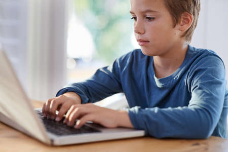 Getting his homework done in a flash. Shot of a young boy using a laptop at home.