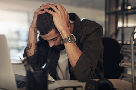 Stress will wear you down if you let it. Shot of a young businessman feeling stressed while working...
