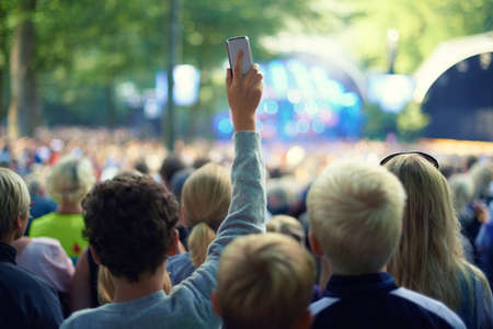 Capture the moment. Shot of a member of the crowd taking a picture with his camera phone at a music...