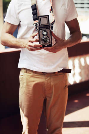 It may be vintage, but classics never get old. Young male photographer in the city with a vintage camera.の写真素材
