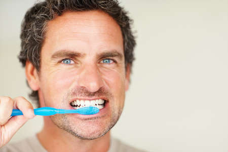 Handsome man brushing teeth. Closeup of handsome mature man brushing his teeth.
