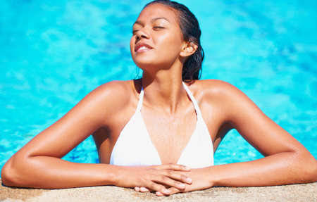 Soaking up the sun. Cropped view of a young woman in a swimming pool enjoying the sun.