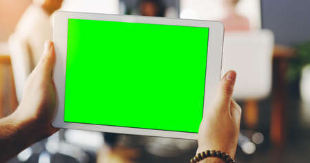 Take a browse. Shot of an unrecognisable businessperson holding a digital tablet with a chroma key screen.の写真素材