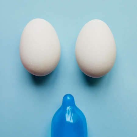 Sorry guys its not happening today. Studio shot of a blue condom and two eggs placed against a blue background.の写真素材