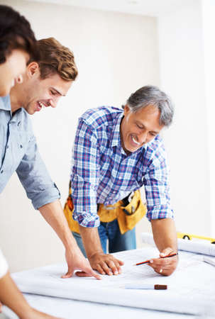 Couple discussing home renovation plan with architect. Happy young couple looking at blueprint with...