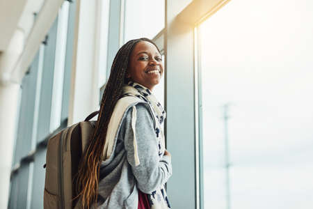This will be my first time flying. Cropped shot of a young woman looking at out the airport window...