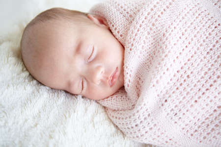 Sweet innocence. A beautiful infant girl sleeping while wrapped up in a blanket.