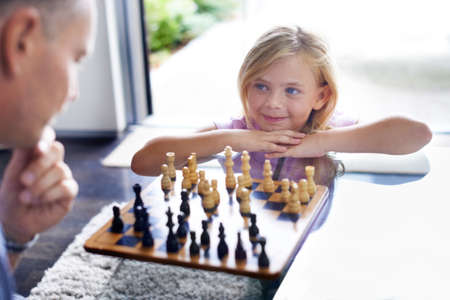 Teaching her the skill of strategy. A father playing chess with his young daughter.の写真素材