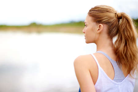 Its all about finding the calm in the chaos. Rearview shot of a young woman sitting outdoors.