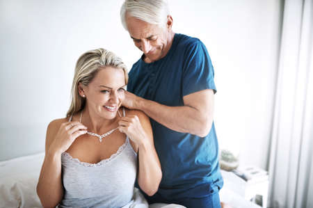 You know just how to spoil me. Shot of a mature man putting a necklace around his wifes neck at...