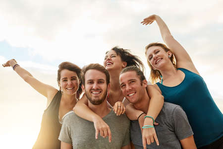 The beach is where we want to be. Portrait of a group of happy young friends posing with their arms...