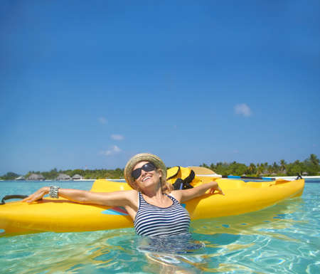 The most relaxing holiday. A beautiful young woman relaxing in a tropical ocean with her boat.の写真素材