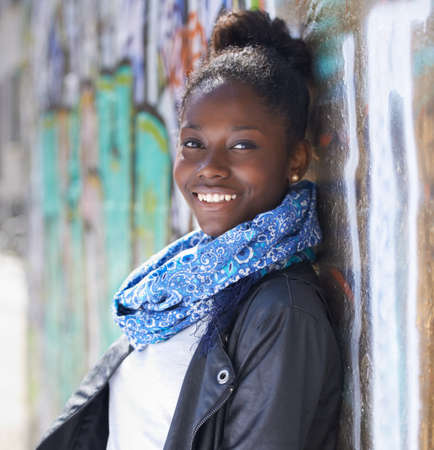 Ready for her future. Portrait of a beautiful young woman leaning against a wall in the city.の写真素材