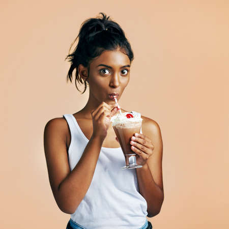 Milkshake is my favourite. Studio portrait of a beautiful young woman posing with a chocolate...