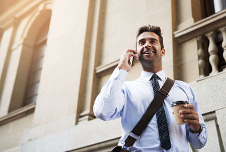 Hello yes this is him speaking. Shot of a handsome young businessman talking on his cellphone while...