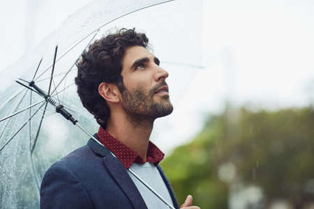 What a beautiful day. Cropped shot of a handsome young businessman on his morning commute in the rain.の写真素材