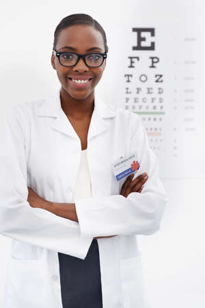 How clearly can you see. Portrait of a female optometrist standing beside a eye test chart.の写真素材