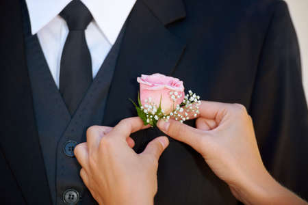 The final touch. Cropped image of a groom getting his boutonniere adjusted before the wedding ceremony.の写真素材