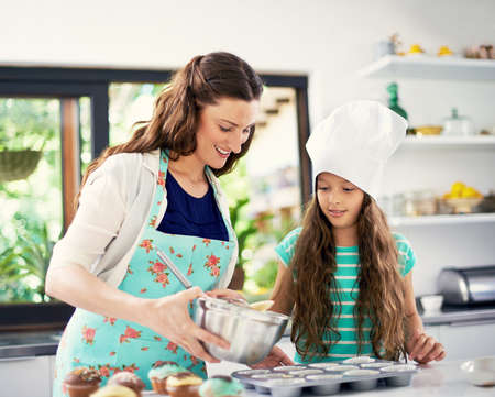 Its cupcake oclock. Shot of a mother and her daughter cooking in the kitchen.
