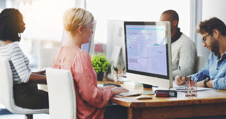 Hard at work in pursuit of success. Shot of a group of businesspeople working on computers in an office.の写真素材