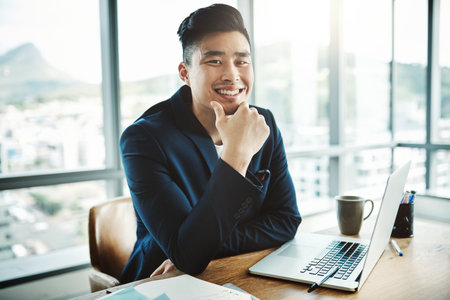 More than a job, its a career. Portrait of a happy young businessman working at his desk in a modern...