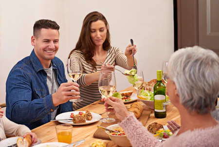 Cheers. Cropped shot of a family sharing a meal around the dinner table.