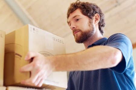 Stacking up another batch. Shot of a young man stacking boxes.の写真素材