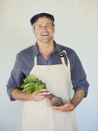On his way to the market. A mature man holding a bunch of beetroot.