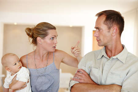Wasnt me. A couple having an argument while standing in their home with their baby.の写真素材