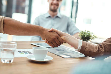 Its a new merger. Shot of two businesspeople shaking hands in an office.の写真素材