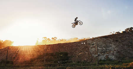 Theres not a competitor in sight. Shot of a motocross rider going over a jump during a race.の写真素材