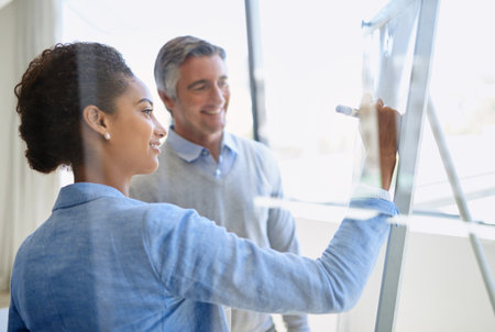 They value each others expertise. Shot of two coworkers discussing ideas while standing by a whiteboard.の写真素材