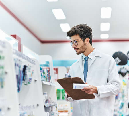 Hes got stock of the medication you need. Shot of a pharmacist working in a pharmacy.の写真素材