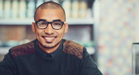 Im here for my daily dose of caffeine. Portrait of a young man sitting in a cafe.