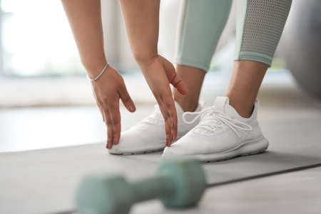 Bend down and touch your feet. Closeup shot of an unrecognisable woman stretching to touch her toes while exercising at home.の写真素材