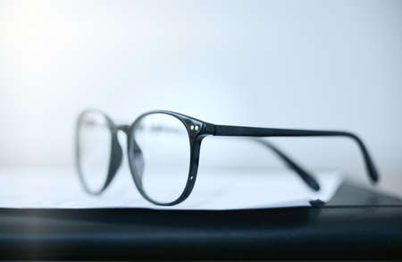 Keep the vision clear. Shot of a pair of glasses lying on a desk in an empty office during the day.の写真素材