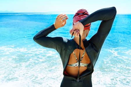 Preparing for the open water. Rearview shot of a female open water swimmer preparing to enter the...