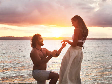 He popped the question at the most scenic place. Shot of a young man proposing to his girlfriend at the beach.の写真素材
