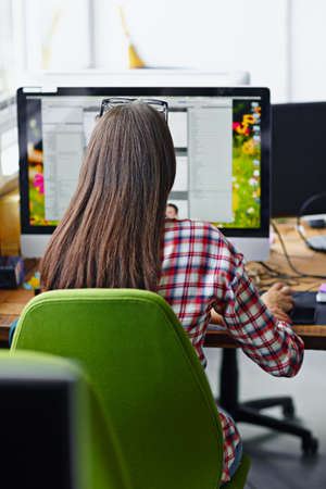 Shes glued to the screen. Rearview shot of a female designer working on her computer.