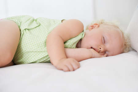 Lost in dreamland. A cute baby girl fast asleep with her thumb in her mouth.の写真素材
