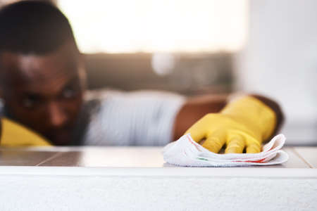 I prefer my home to be spotless. Cropped shot of an unrecognizable man cleaning a kitchen counter at home.の写真素材