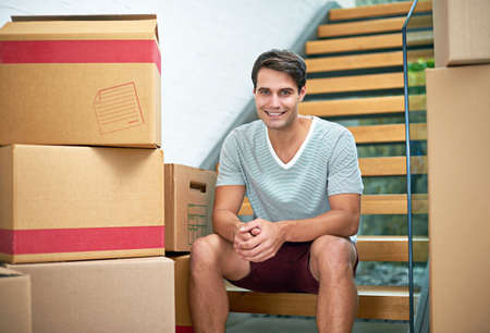 The start of a new chapter. Portrait of a young man sitting in his new home surrounded by cardboard...